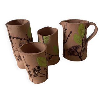 Artisanal pottery set in red clay with harmonious plant motifs