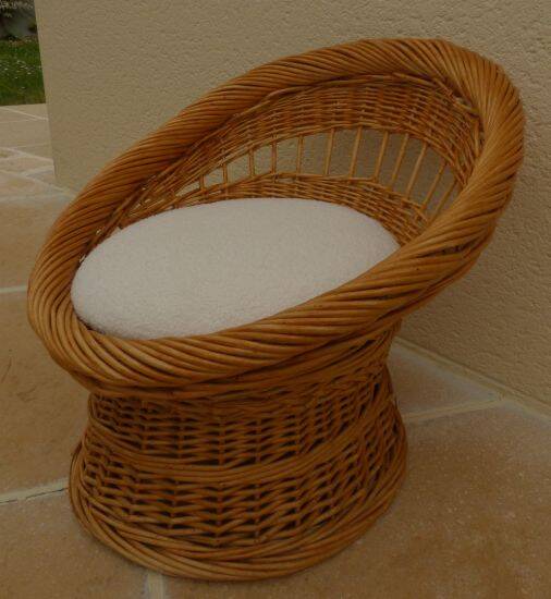 Wicker armchair with a high back and its boucle fabric cushion.