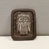 Small relief with a motif of an owl emerging from the back plate.