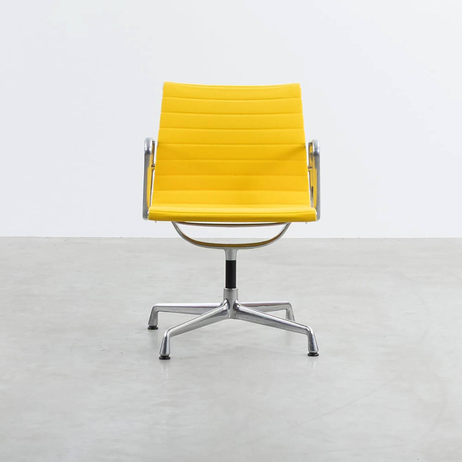 Fauteuil Aluminum Group EA107 de Charles et Ray Eames en tissu jaune.