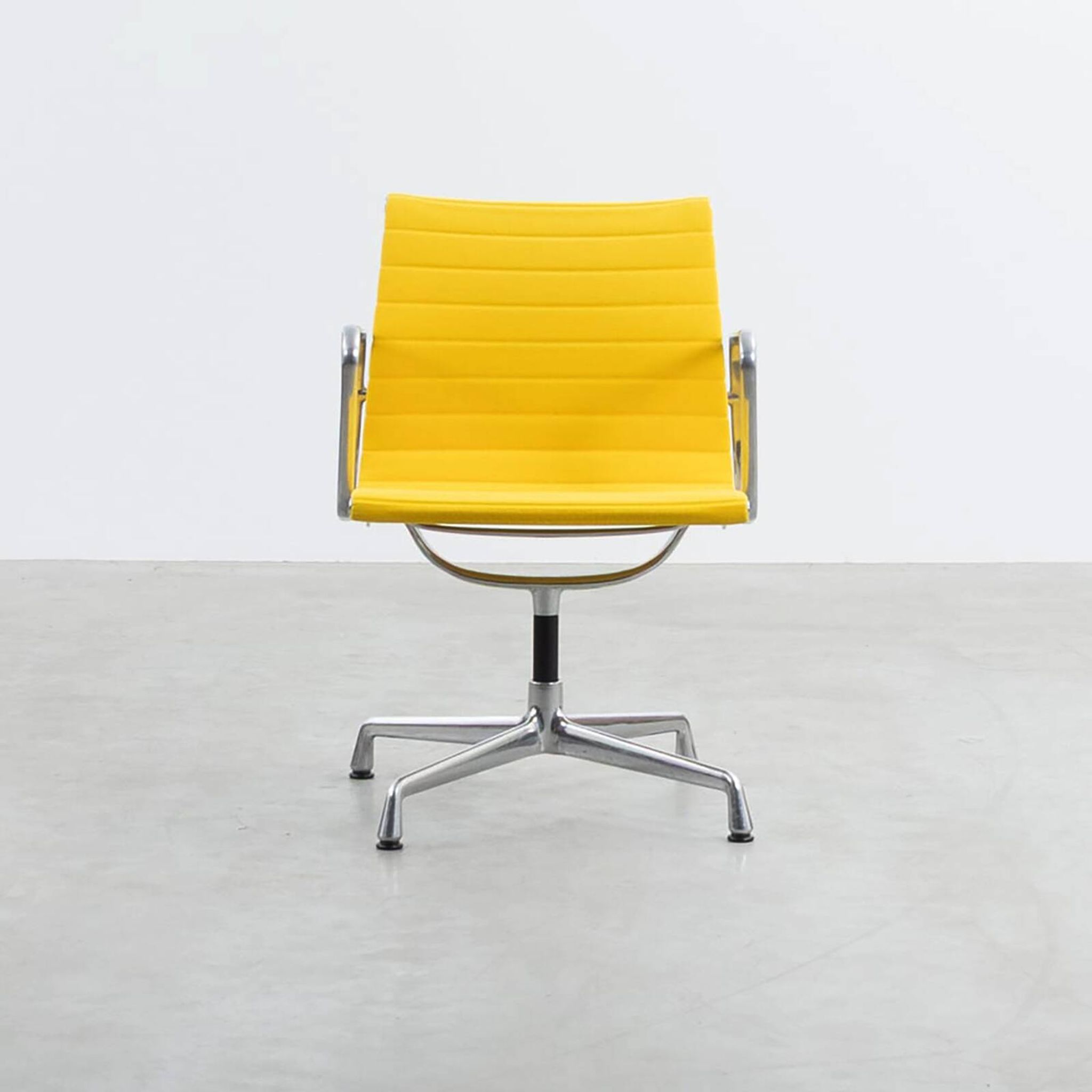 Fauteuil Aluminum Group EA107 de Charles et Ray Eames en tissu jaune.