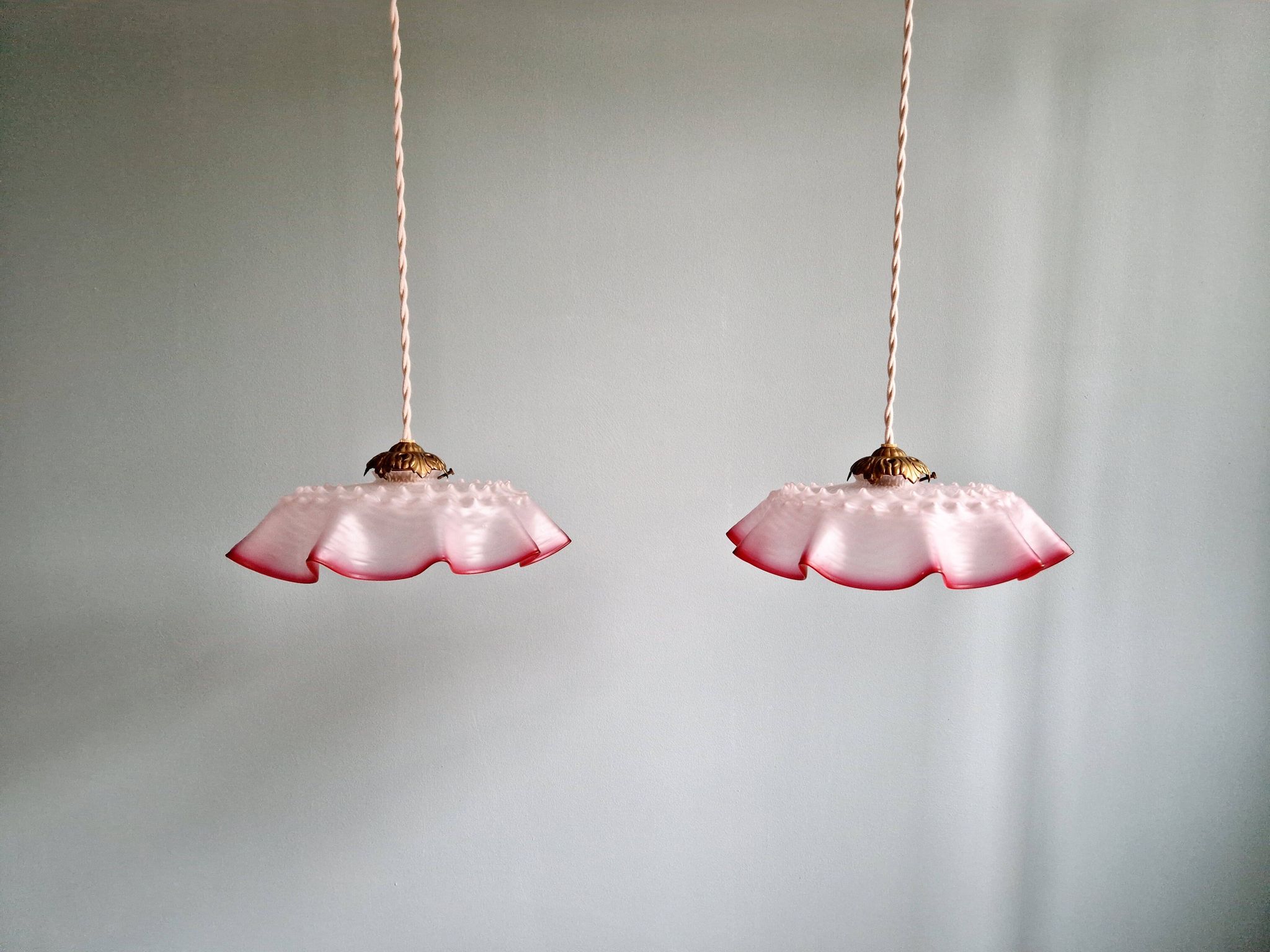 Pair of clear and pink satin glass scalloped pendant lights, 1920s-30s