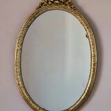 Oval mirror in gilded wood with a pediment.