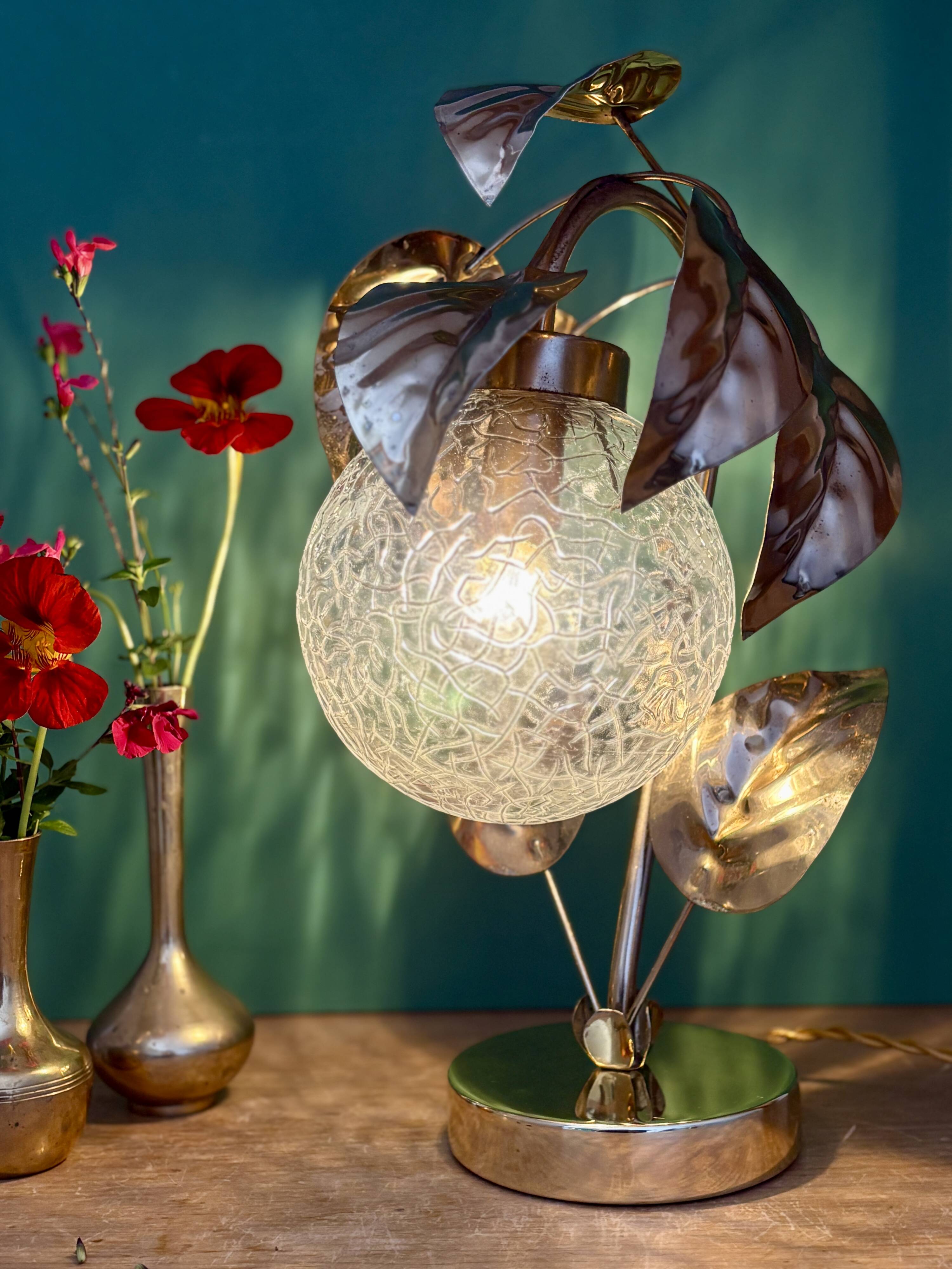Vintage lamp with brass leaf design and transparent glass globe.