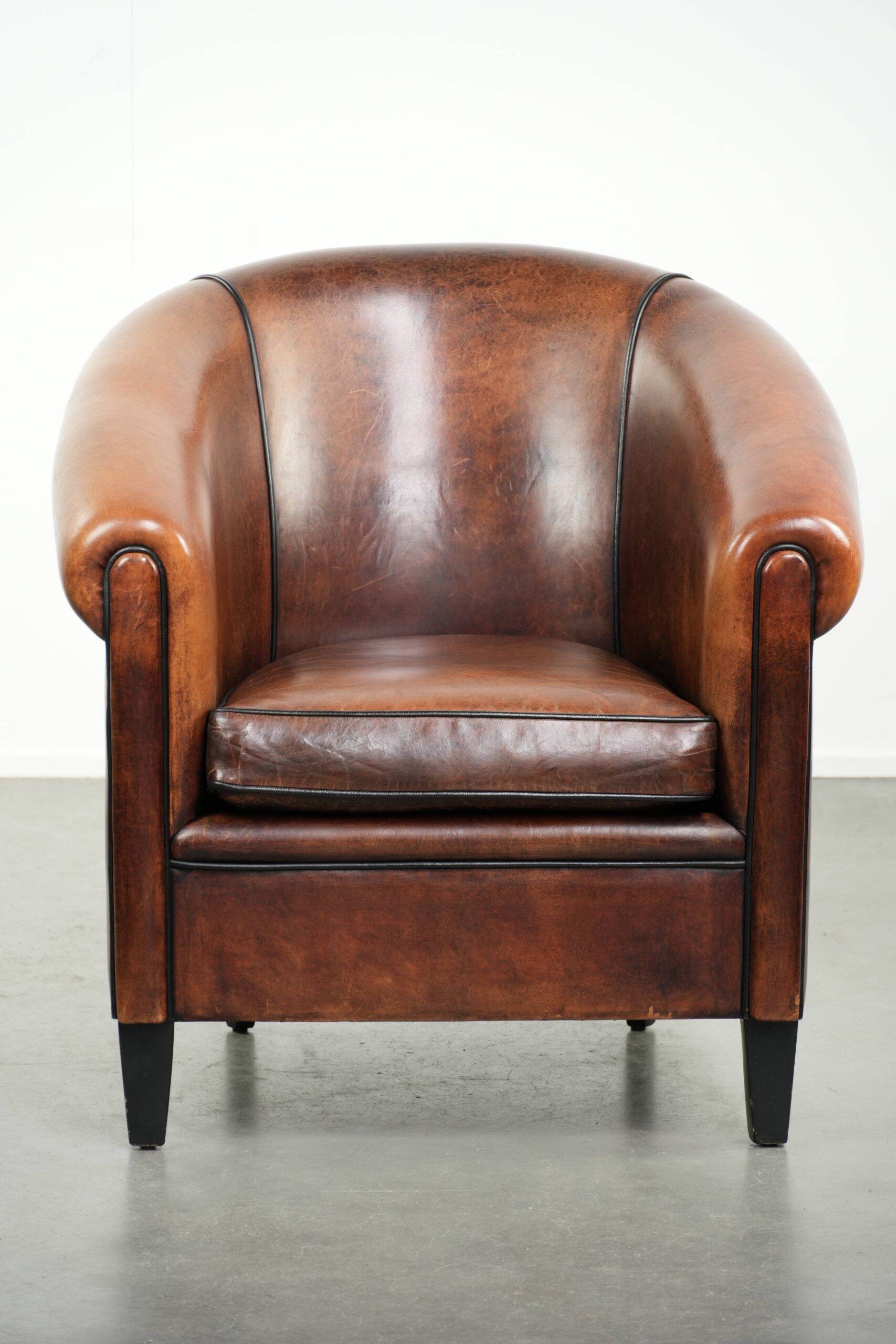 Sheepskin club armchair with deep warm colours and black piping