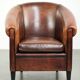 Sheepskin club armchair with deep warm colours and black piping