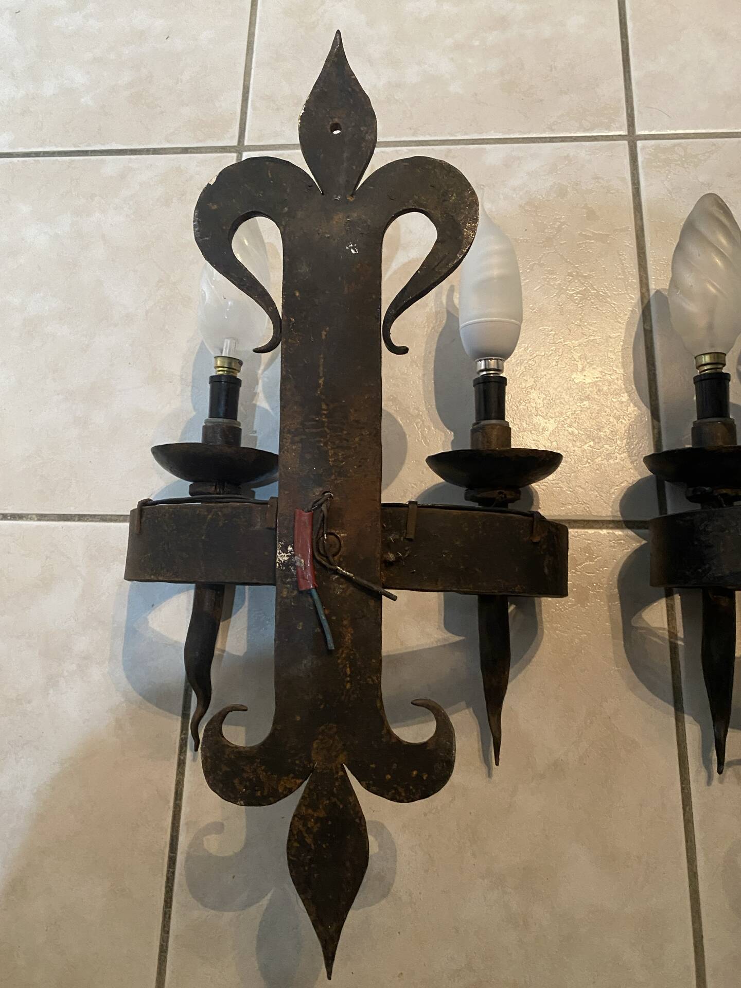 Pair of wrought iron wall lights in fleur-de-lis château style.
