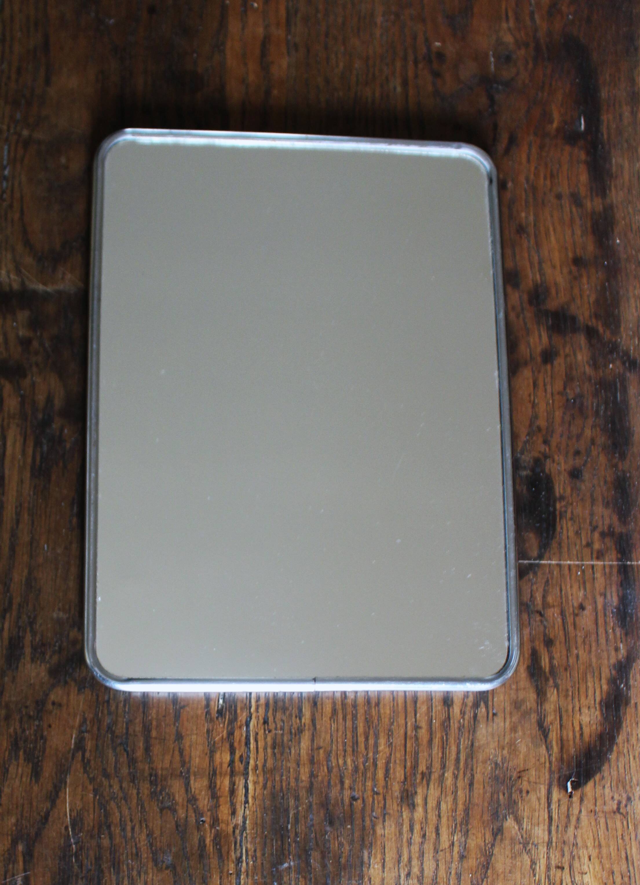 Simple rectangular barber mirror with a stand.