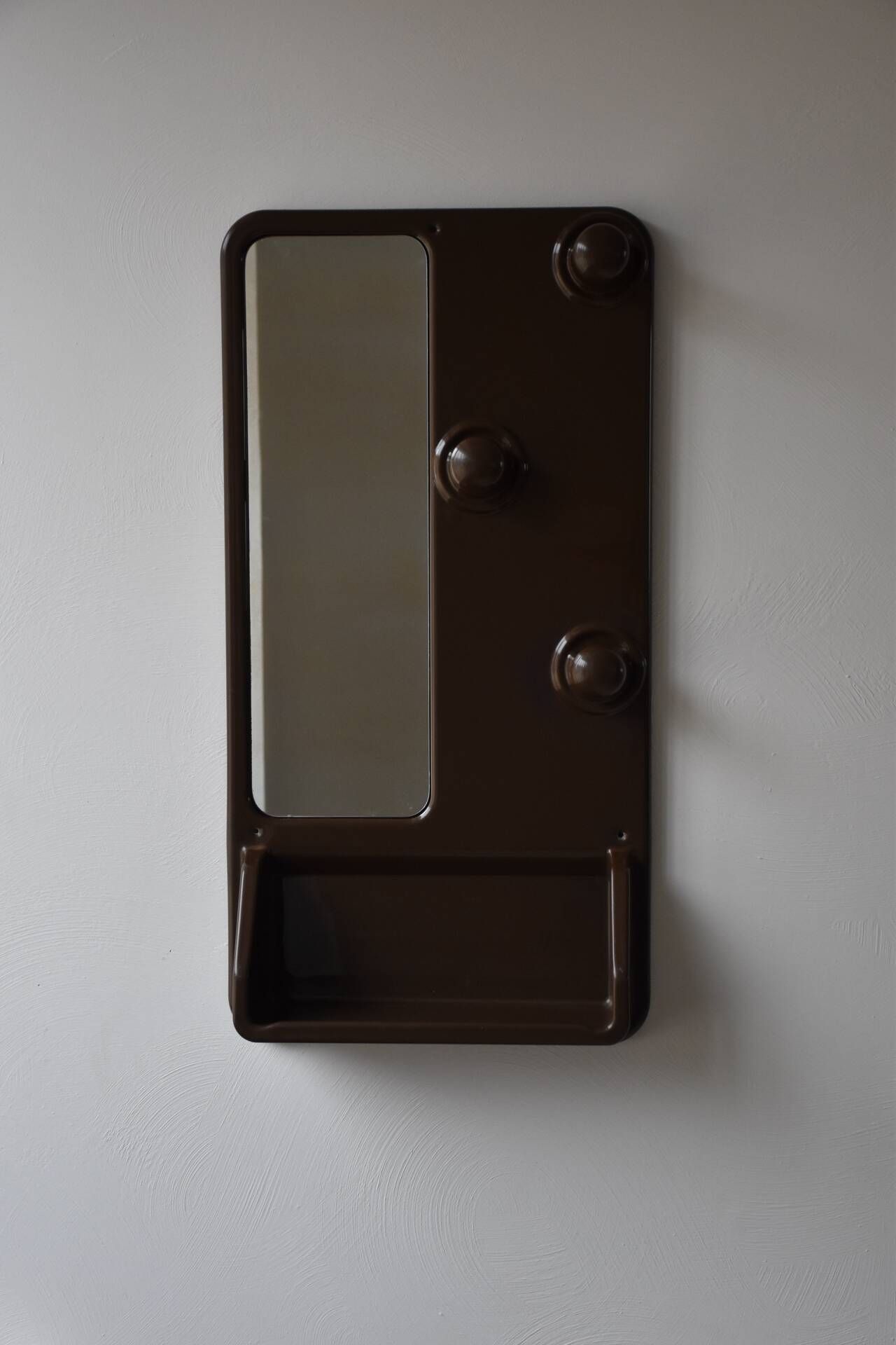 Wall mirror in moulded plastic with hooks and shelf.