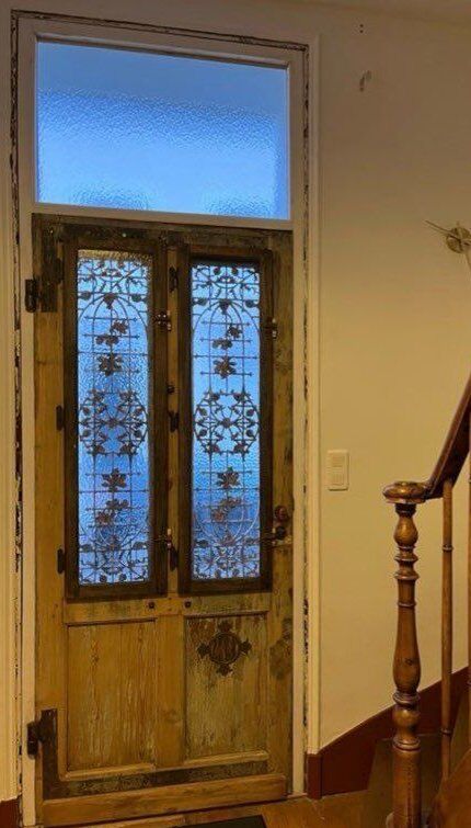 Front door of a house or building in the city centre, with a dolphin door knocker and frame + transom.