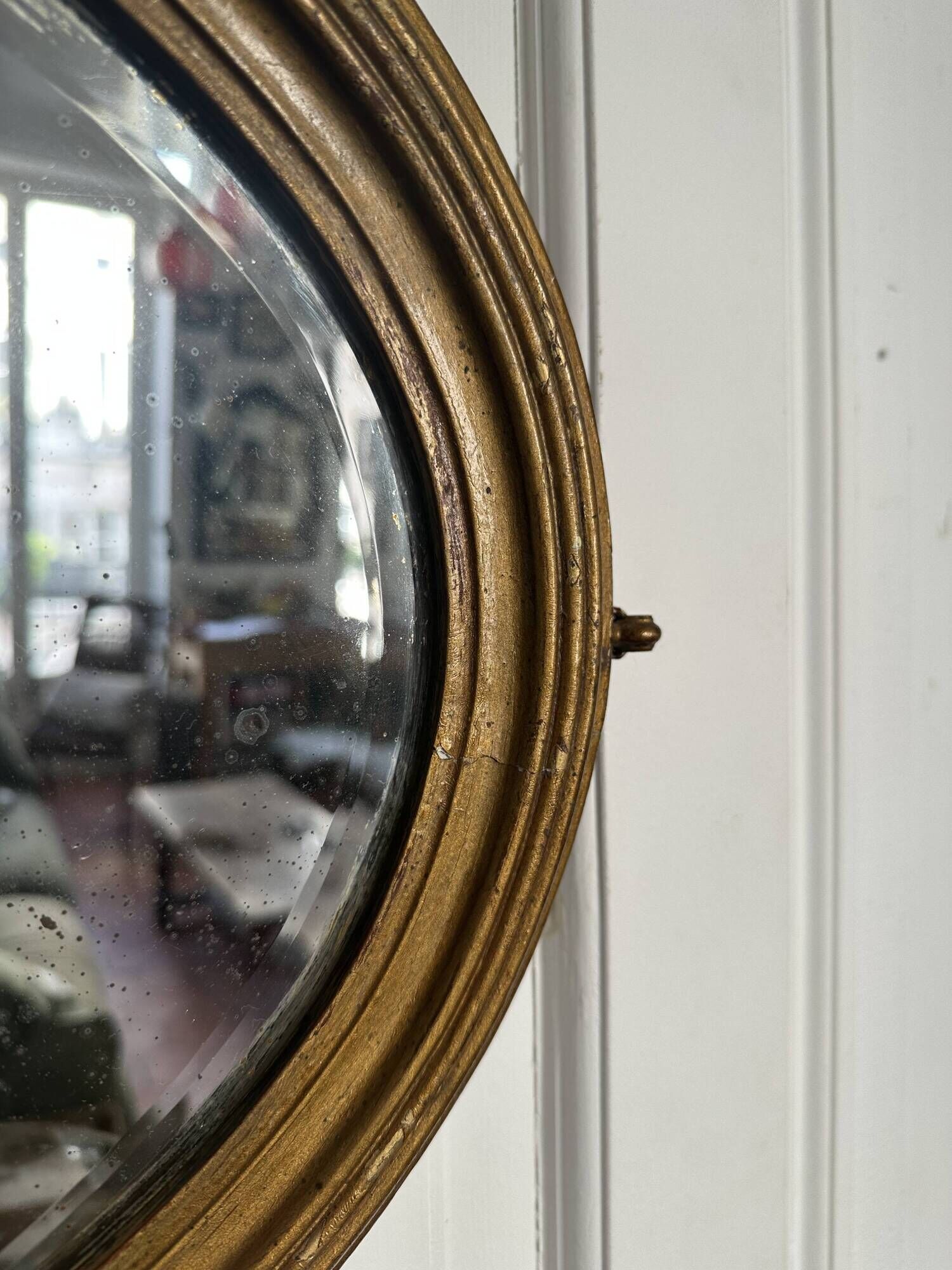 Antique oval mirror in gilded wood, bevelled mercury glass, 19th century.