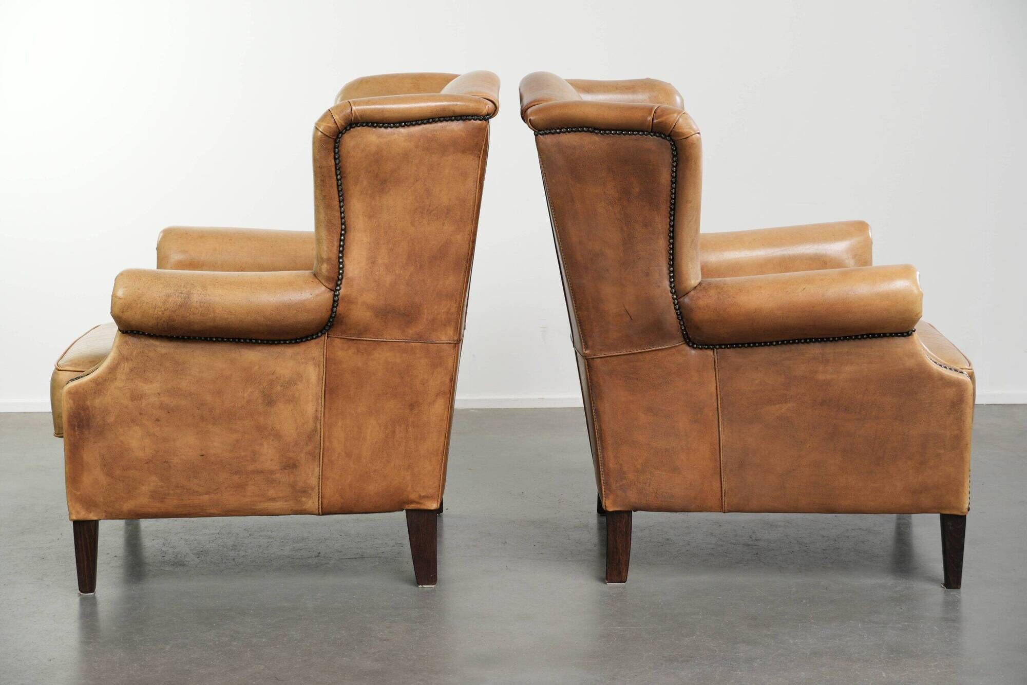Set of two light cowhide wingback armchairs with a timeless English look