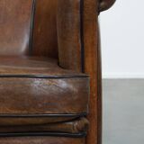 Fauteuil club en cuir de mouton foncé avec passepoil noir