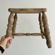 Antique wooden stool with four turned legs.