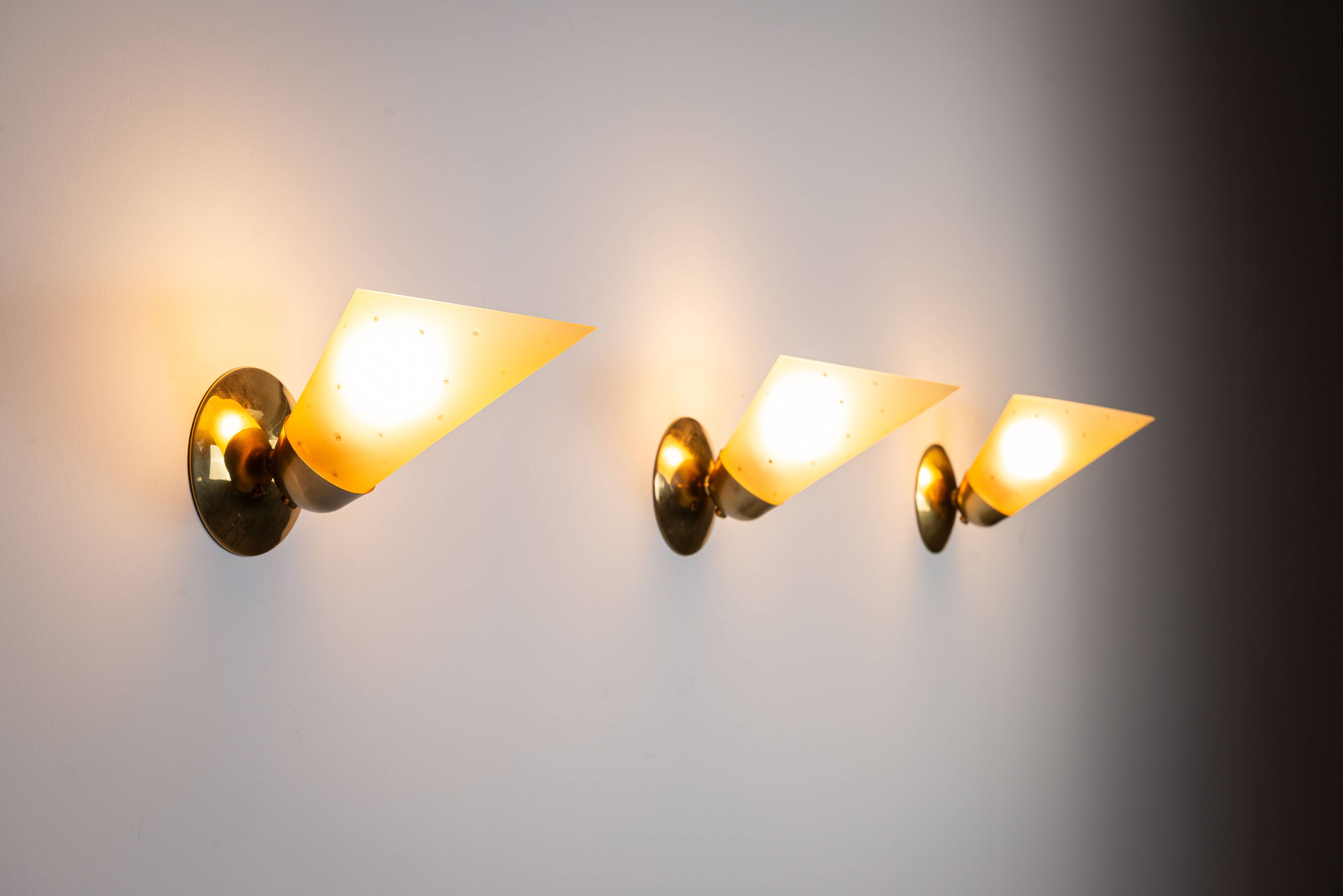 Set of three brass sconces with decorated yellow glass shades