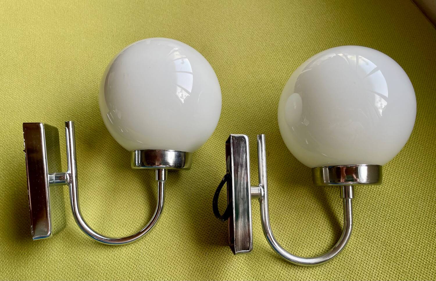 Pair of chrome metal wall lights with white glass globe.