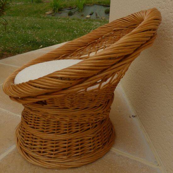 Wicker armchair with a high back and its boucle fabric cushion.