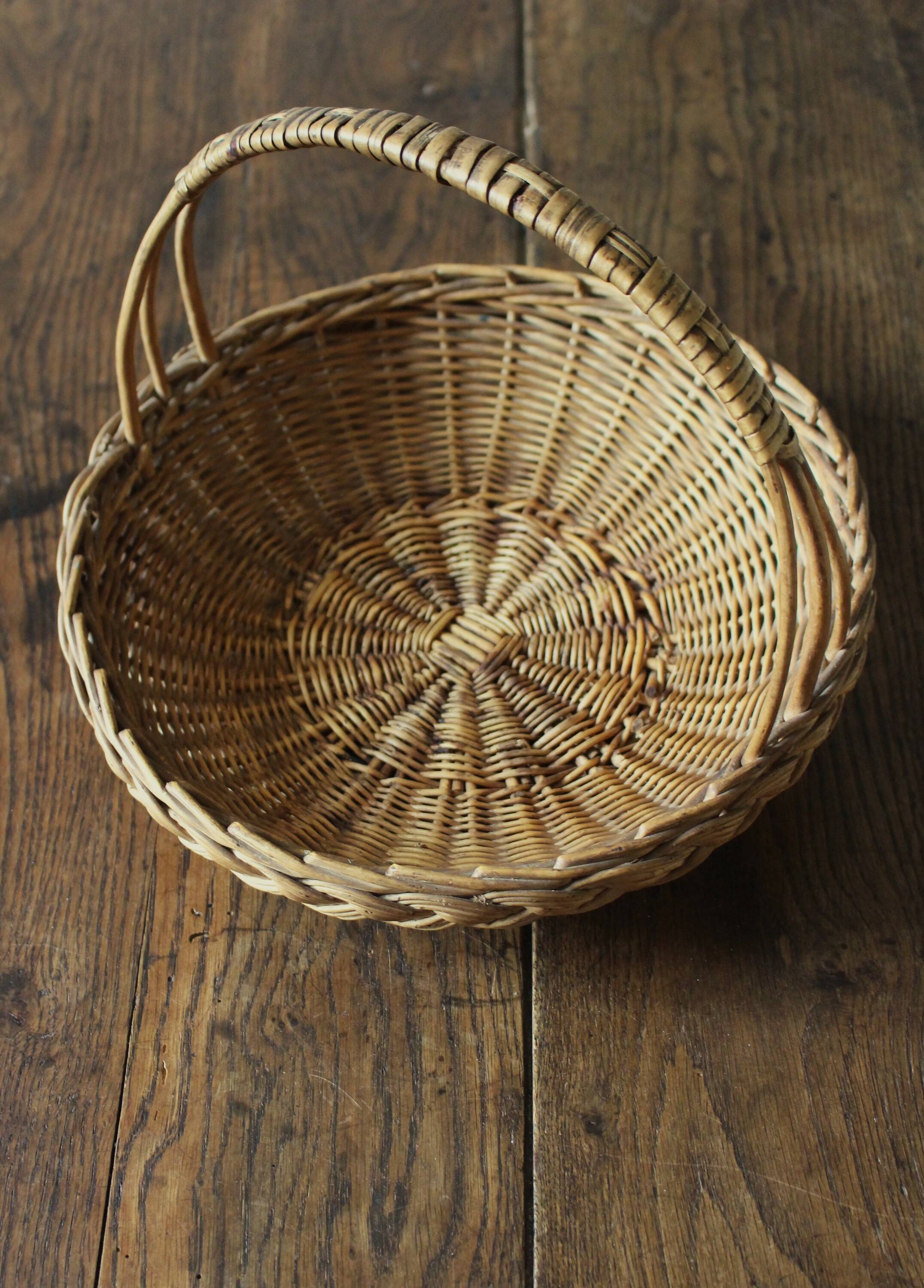 Round wicker basket with a rigid handle.