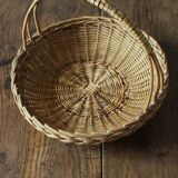 Round wicker basket with a rigid handle.