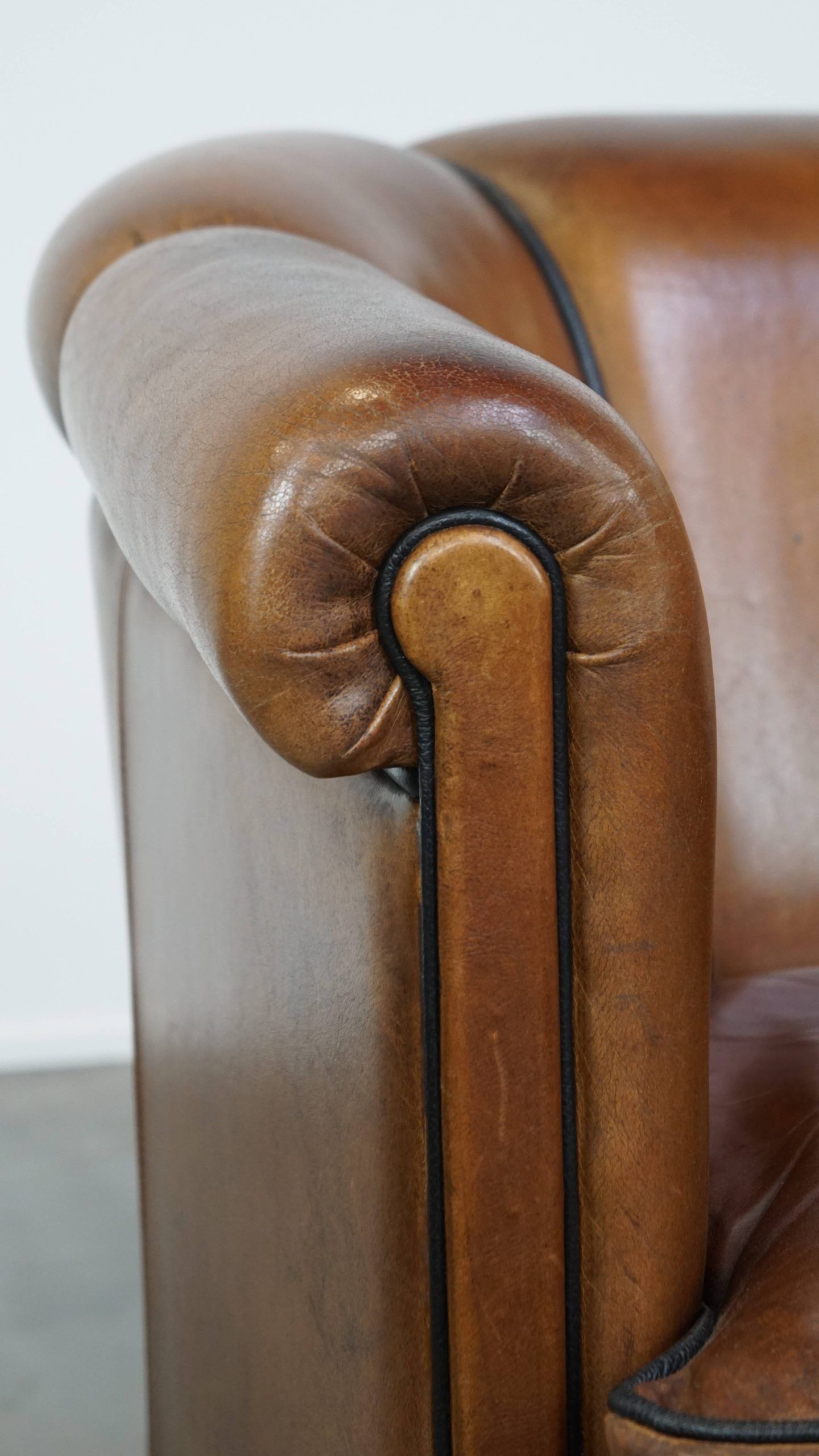 Unique vintage cognac-coloured leather club armchair with black piping