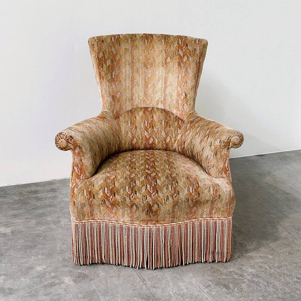 Pair of sculptural Hollywood Regency lounge chairs with original fringed upholstery