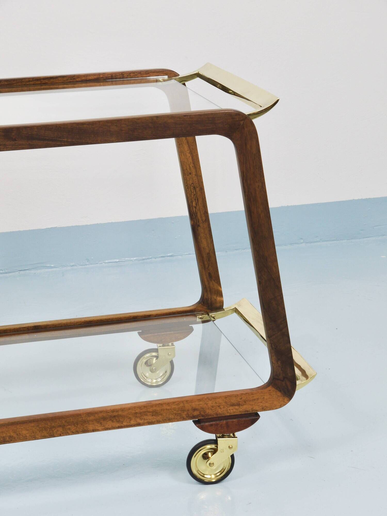 May include: A mid-century modern bar cart with a dark wood frame and two c