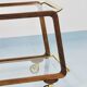 May include: A mid-century modern bar cart with a dark wood frame and two c
