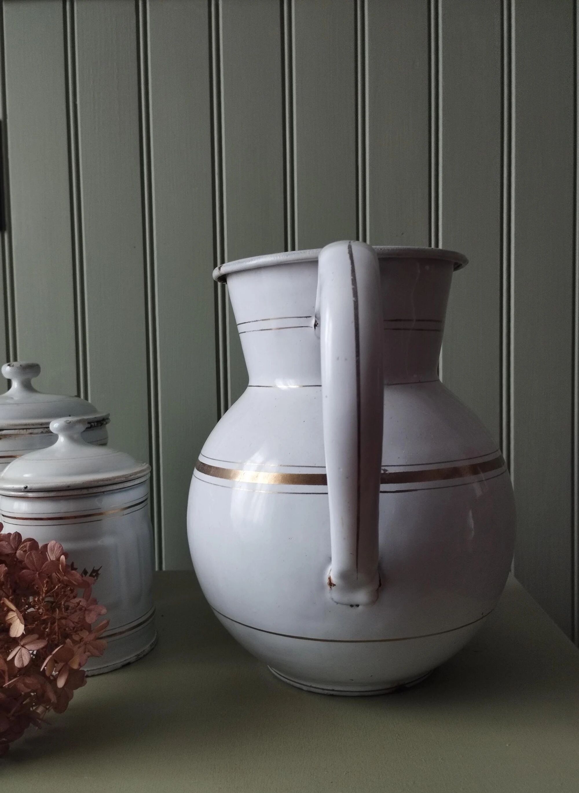 Old enamelled metal jug with gold trim.