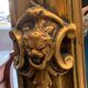 French palace mirror with bow and lion heads, gilded frame.