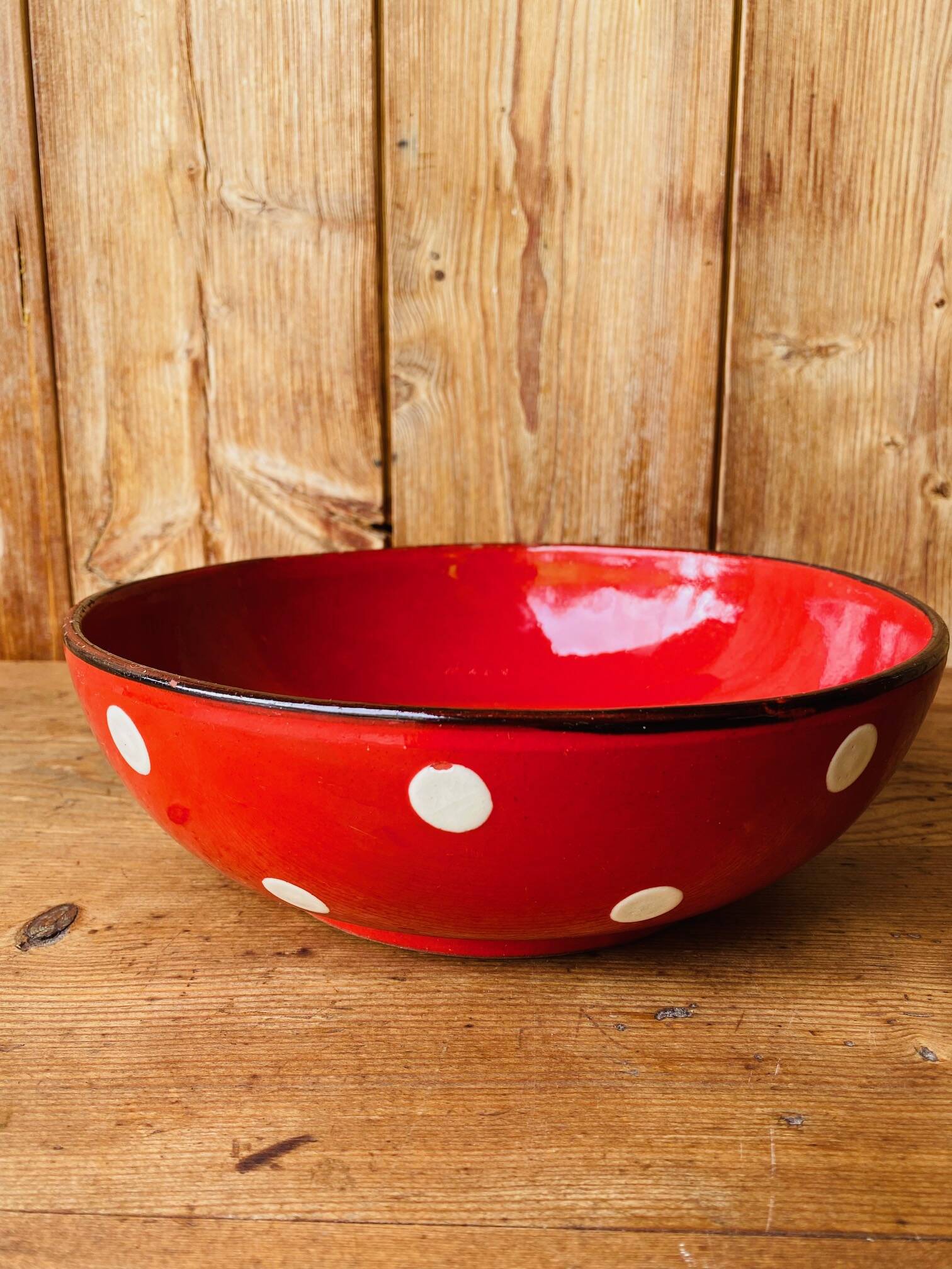 Ceramic salad bowl in red with white polka dots.