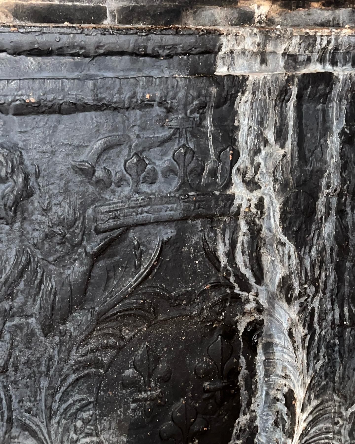 huge old fireplace plate has decoration of angels, crown and fleurs-de-lis