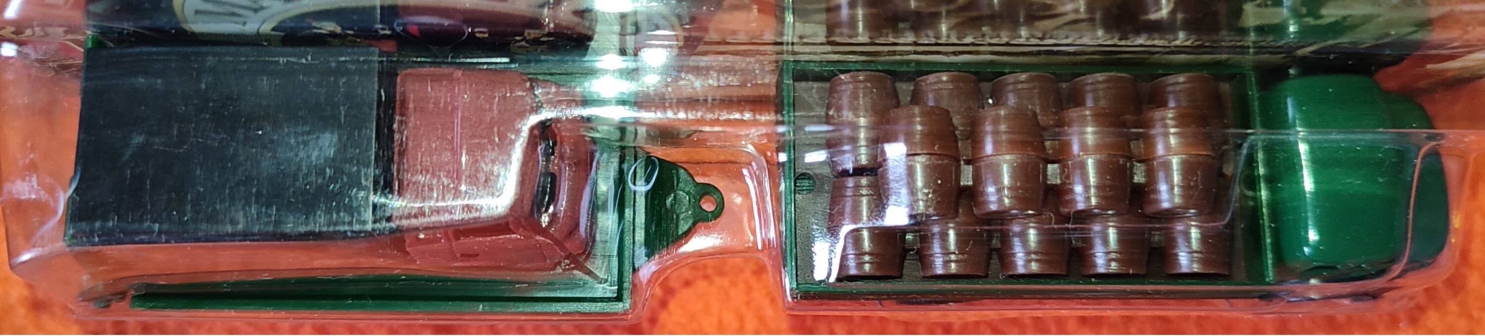 Mercedes flatbed containing drums pulling 1 trailer carrying 1 covered vehicle