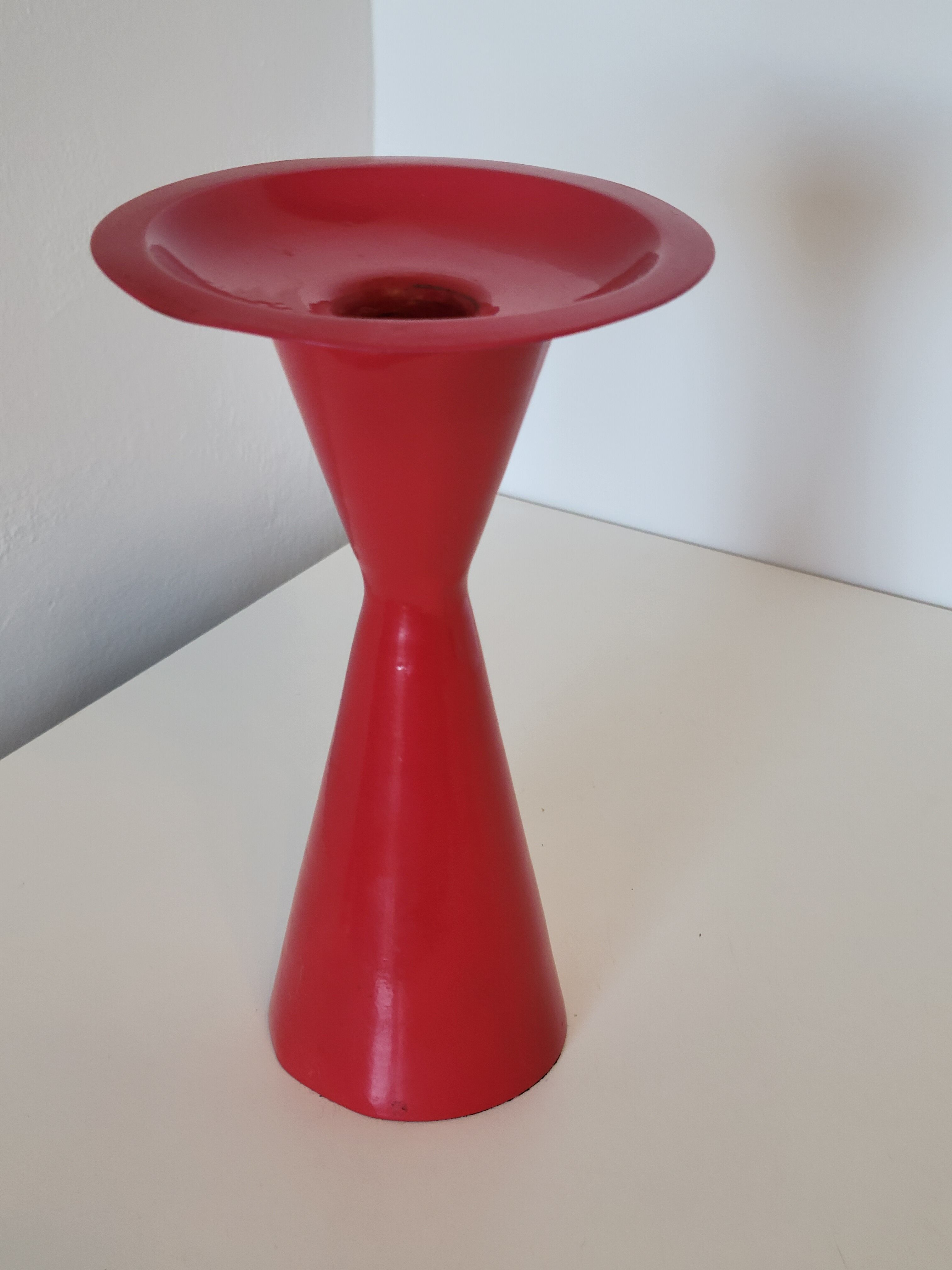Vintage design candlestick in red metal in the shape of an hourglass