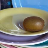 Seven pastel-colored plates mixed with vintage earthenware