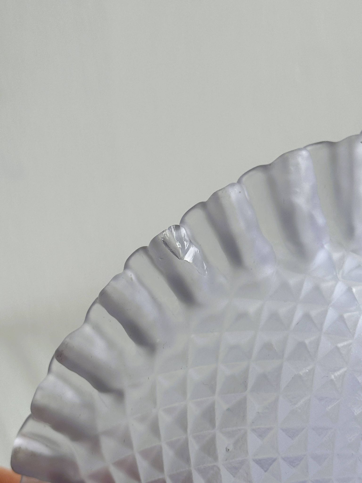 Purple glass pedestal bowl with wavy border and relief pattern.