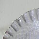 Purple glass pedestal bowl with wavy border and relief pattern.