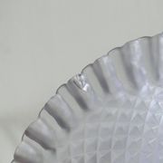 Purple glass pedestal bowl with wavy border and relief pattern.