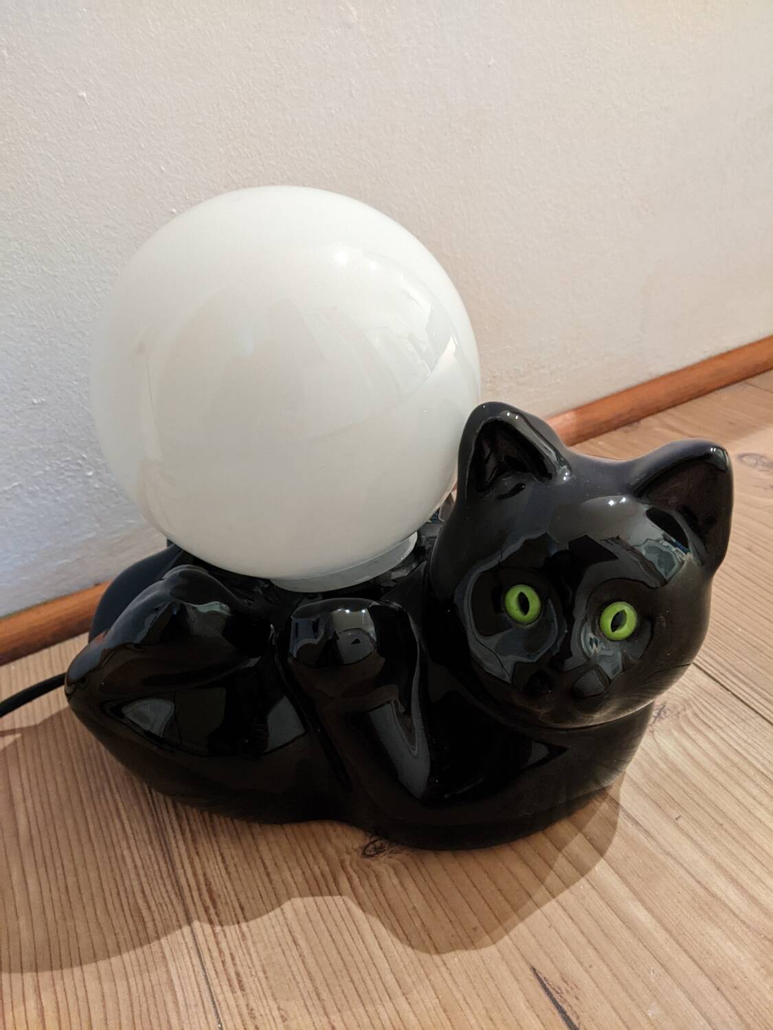 Black cat playing with its globe table lamp