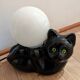 Black cat playing with its globe table lamp