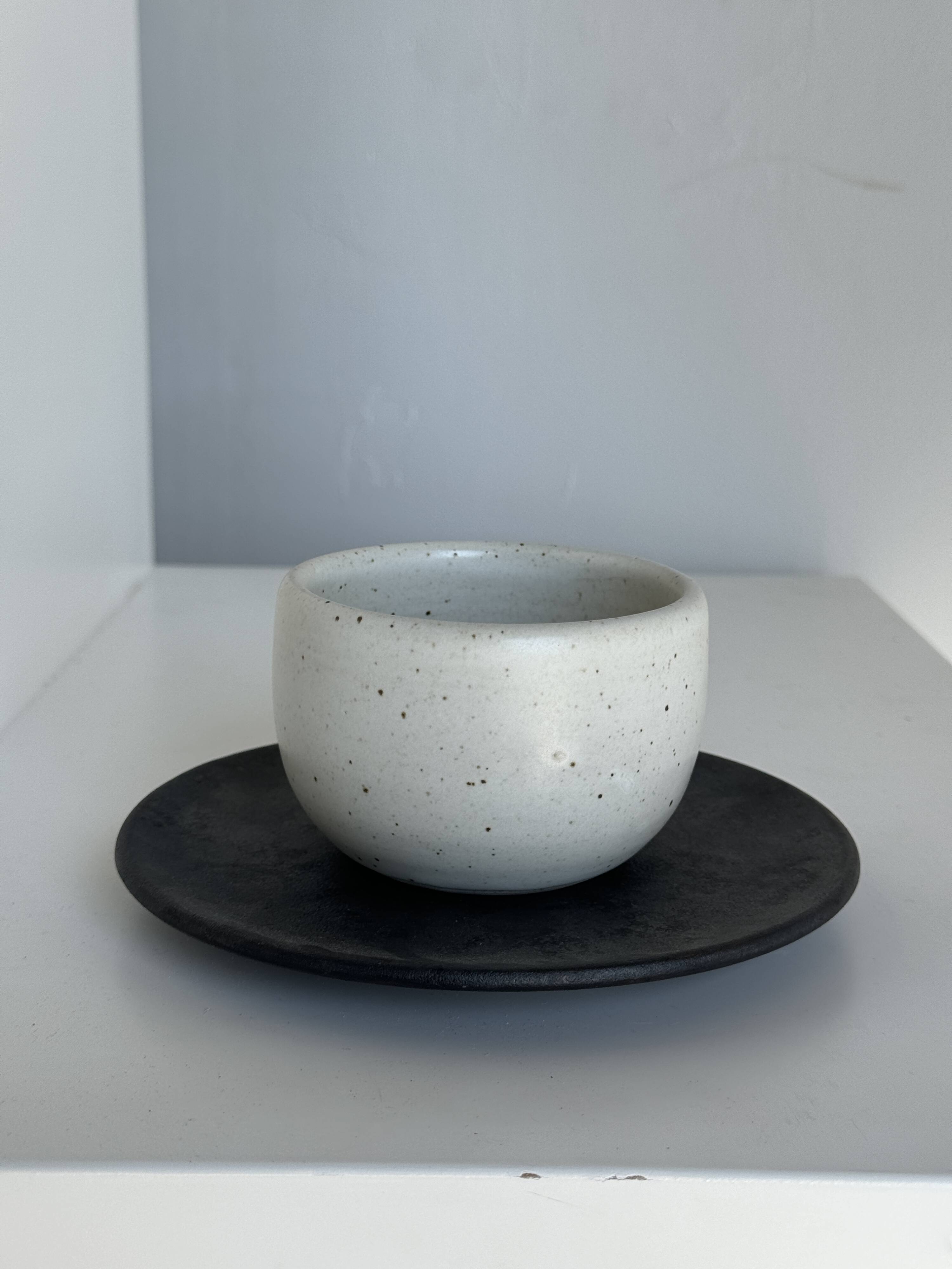 White Indonesian ceramic cup and gray saucer