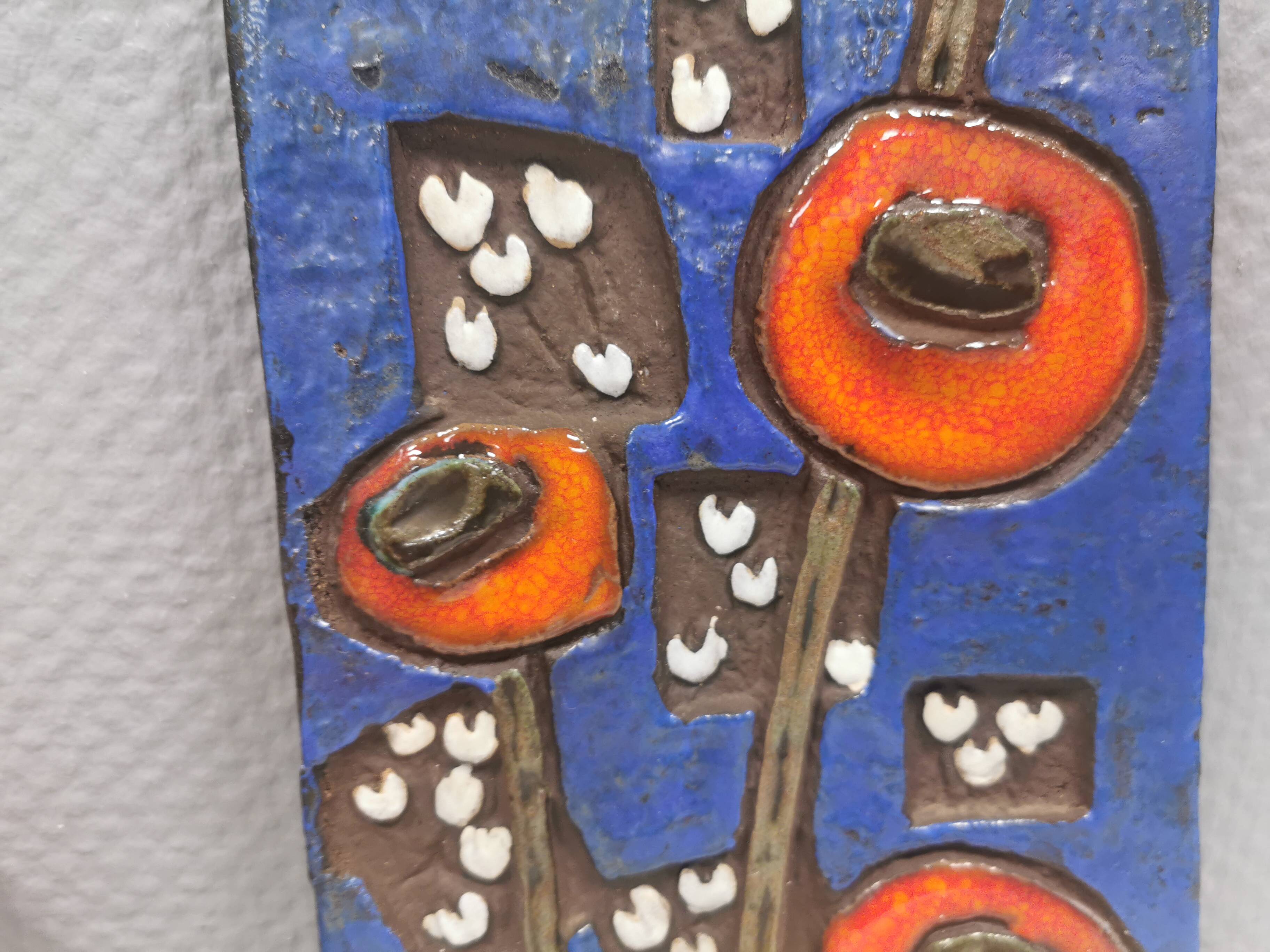 Ceramic relief in attractive blue with a motif of white/red flowers.