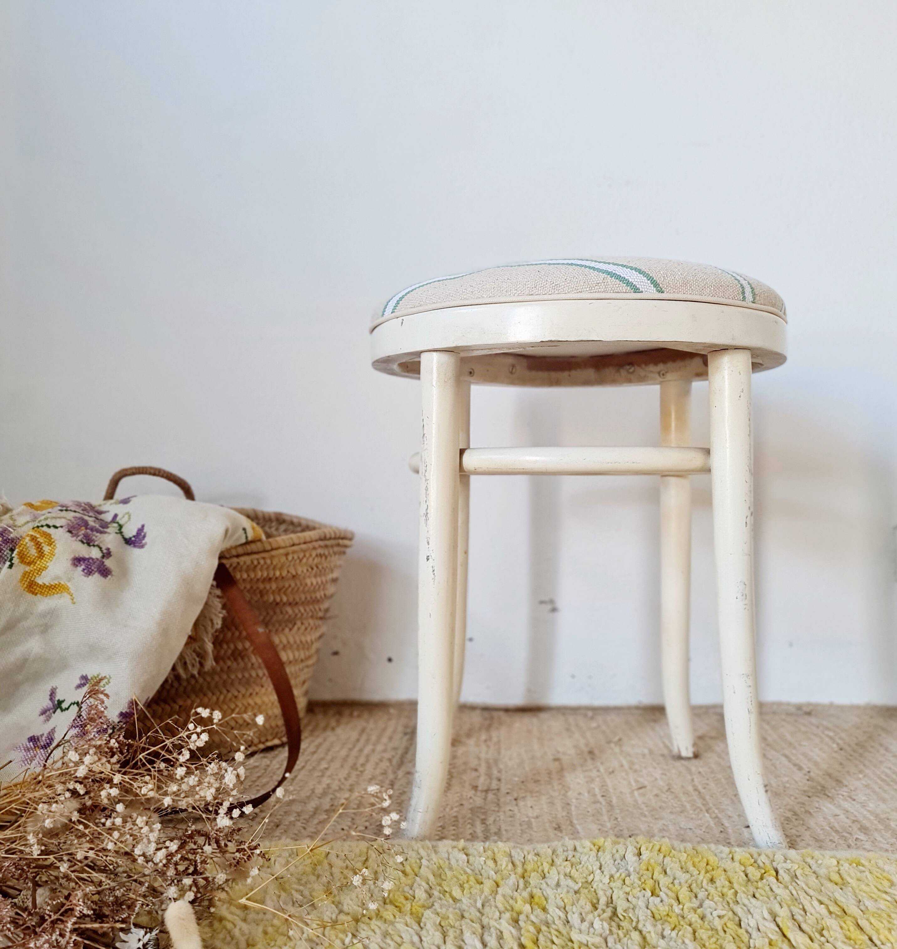 Antique stool with a wooden frame and a cream and green striped fabric seat.
