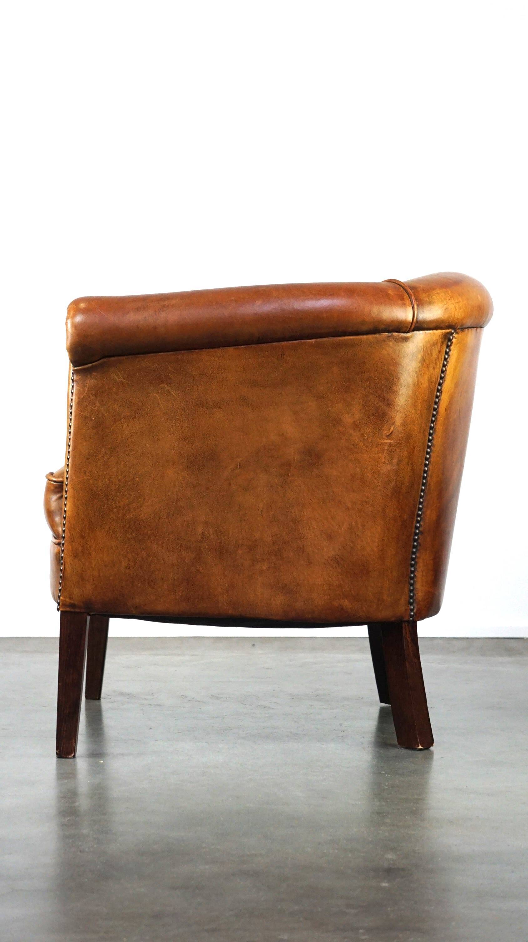 Neat and subtle sheepskin club chair, finished with decorative studs and a fixed seat cushion