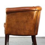 Neat and subtle sheepskin club chair, finished with decorative studs and a fixed seat cushion