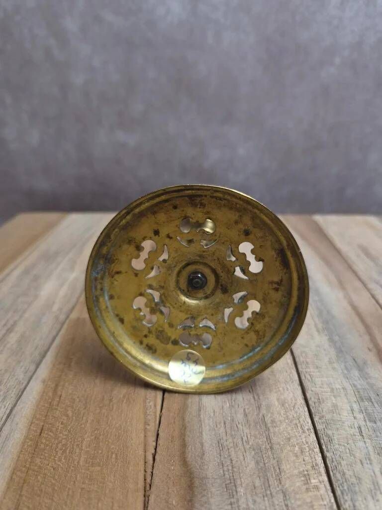 Antique brass candlestick with patina, openwork vintage foliage decoration.