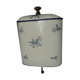 Old wall fountain in enamelled sheet metal decorated with blue flowers on a white background