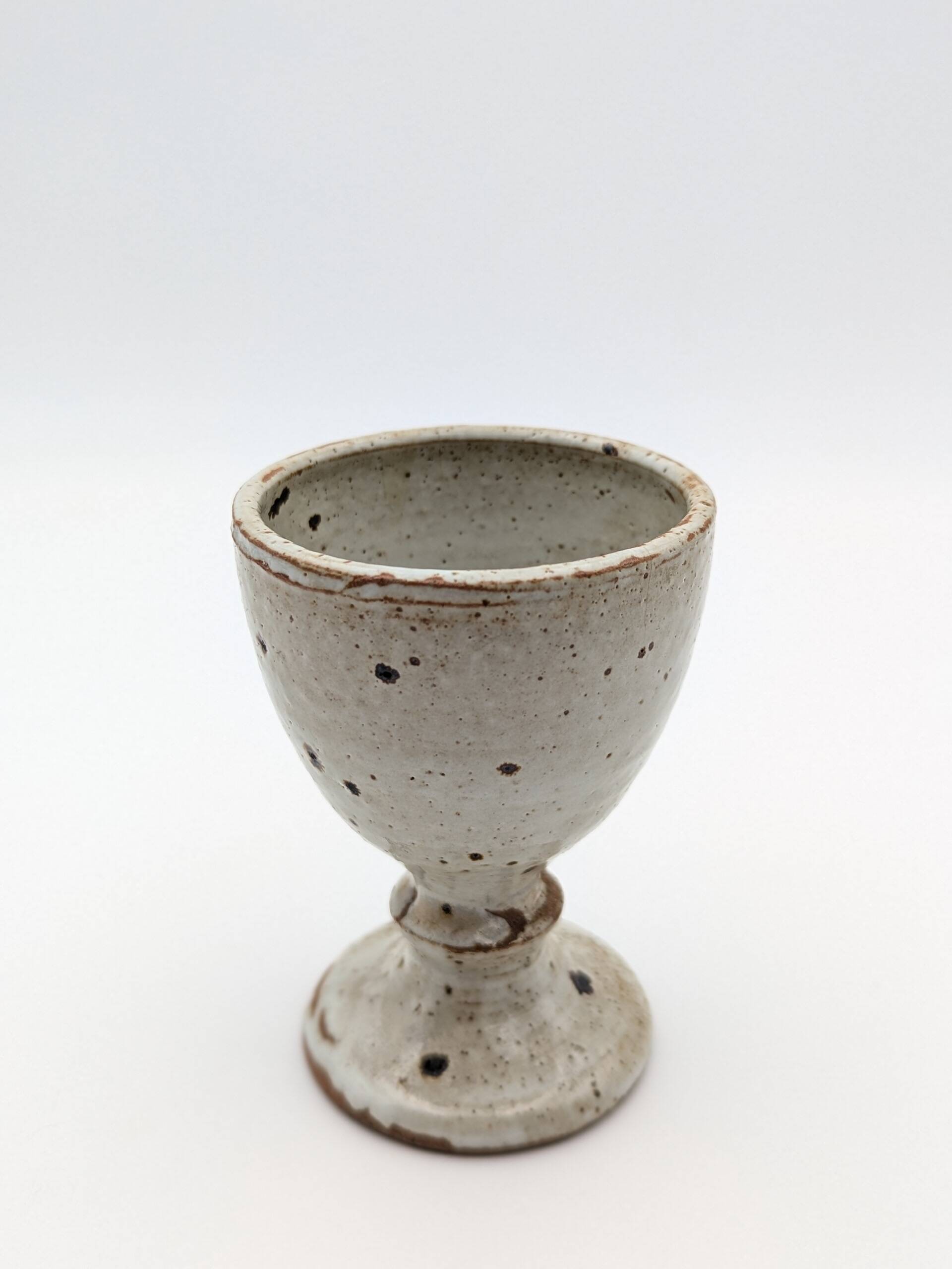 Glass on foot in pearly white stoneware with black spots