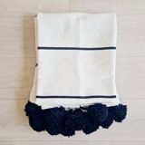 Handwoven throw with black stripes and pom-poms