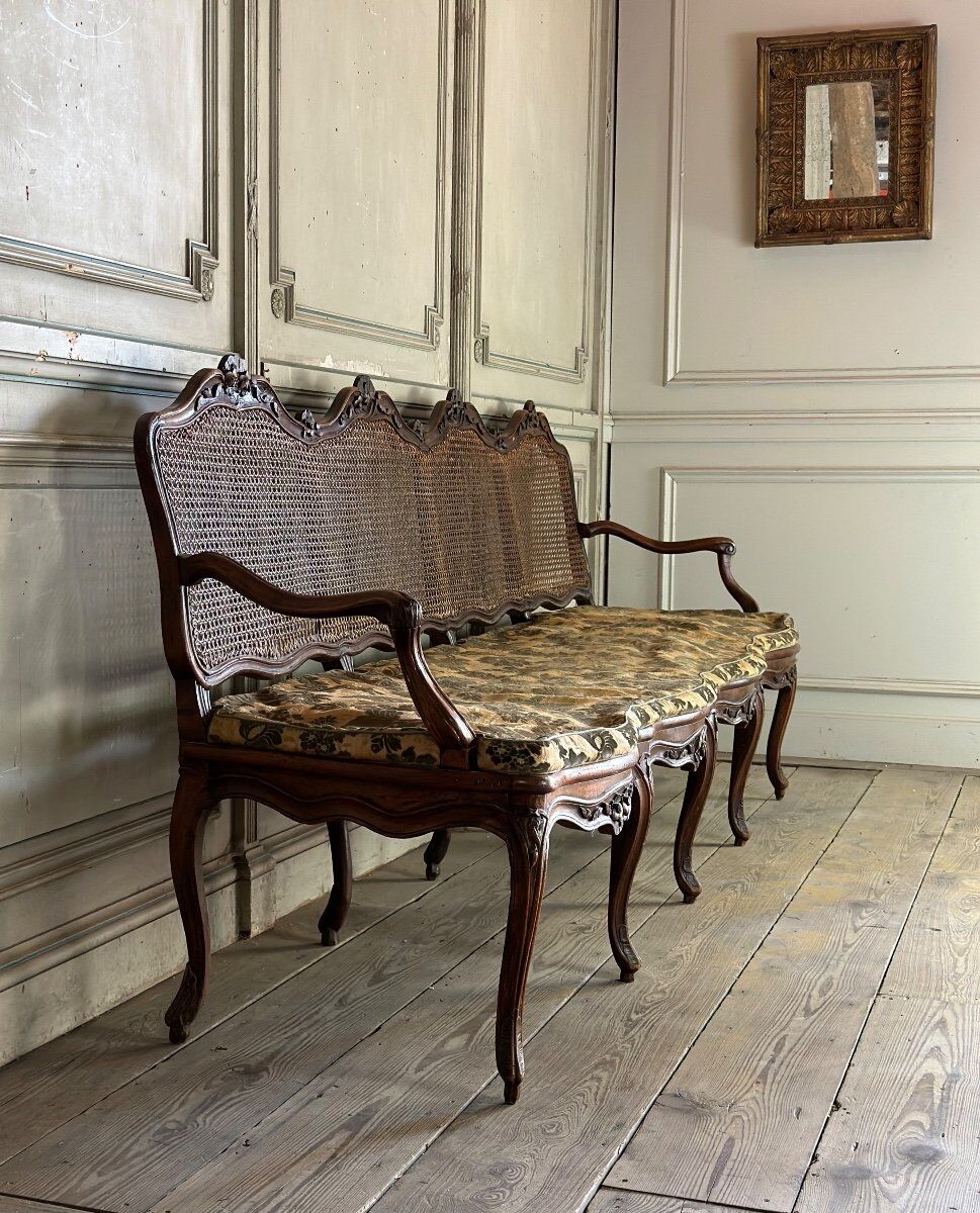 Grande banquette Louis XV en bois naturel mouluré et sculpté, France XVIIIème siècle