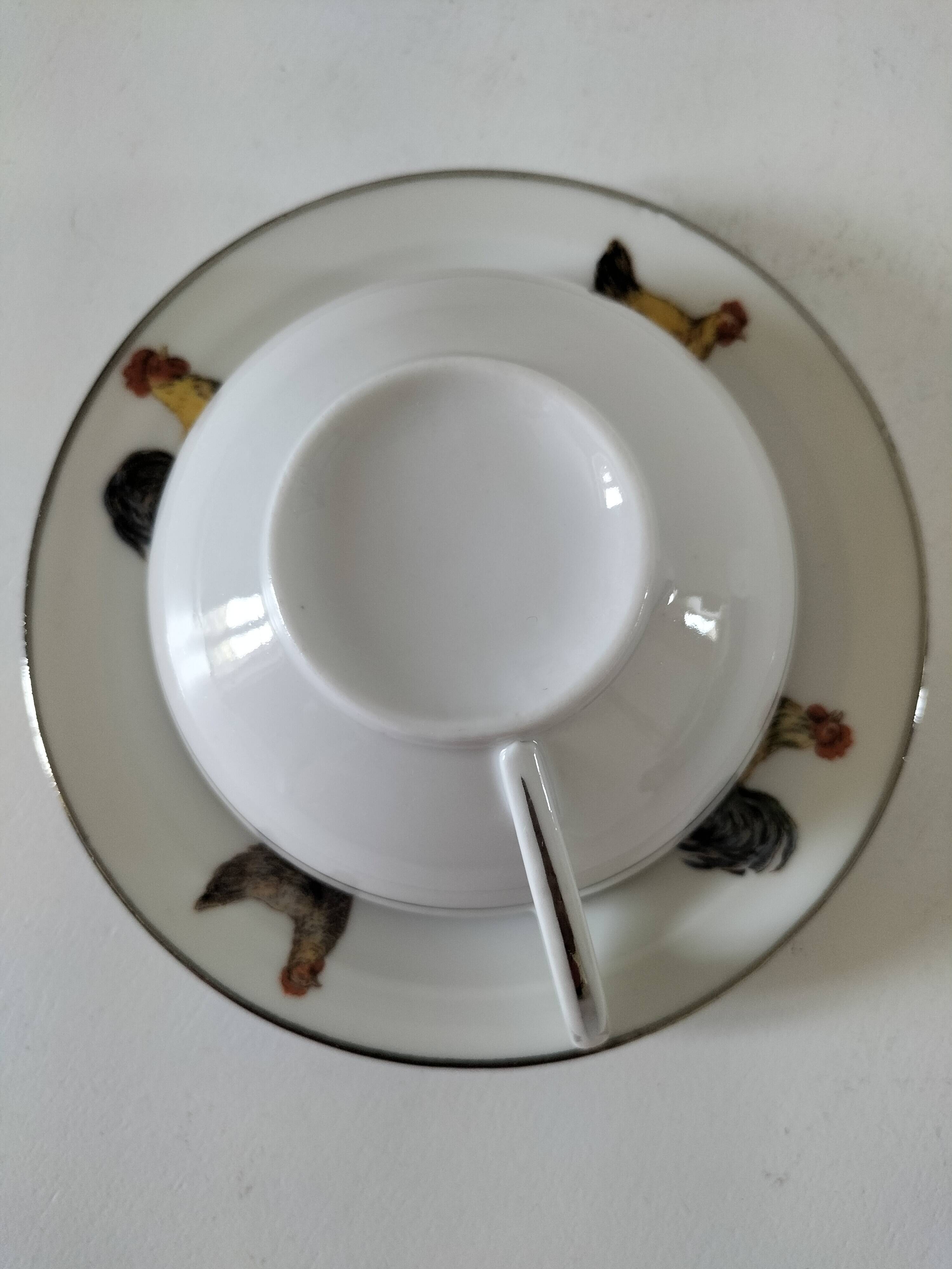 Cup and saucer in porcelain decorated with roosters and hens.